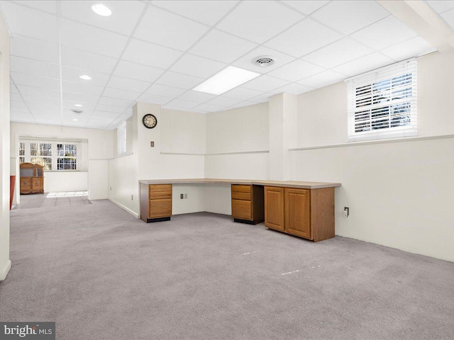 unfurnished office featuring a drop ceiling, light colored carpet, visible vents, and built in study area