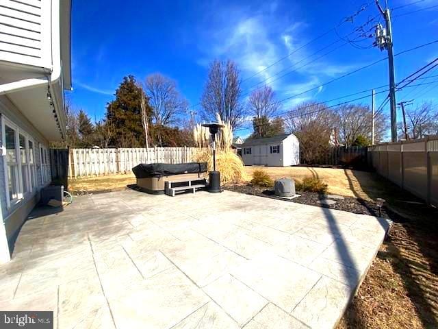 view of patio with an outdoor structure, a fenced backyard, a storage shed, and a hot tub