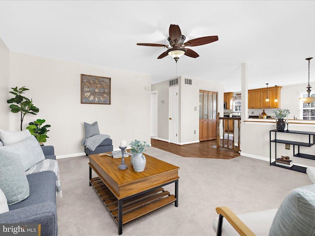 carpeted living room with visible vents, baseboards, and ceiling fan