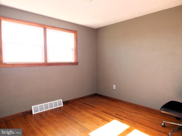 unfurnished room featuring light wood-style flooring, visible vents, and baseboards