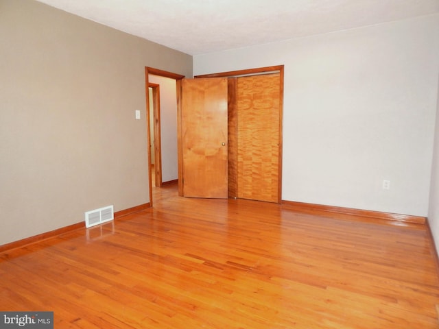 empty room with light wood-style floors, baseboards, and visible vents