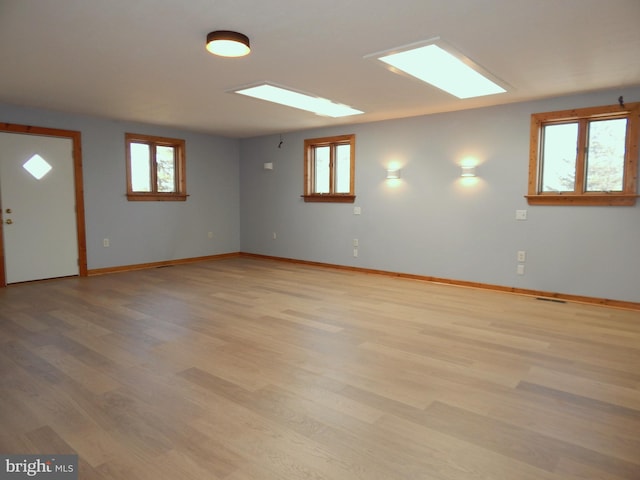 below grade area with a healthy amount of sunlight, light wood finished floors, and baseboards