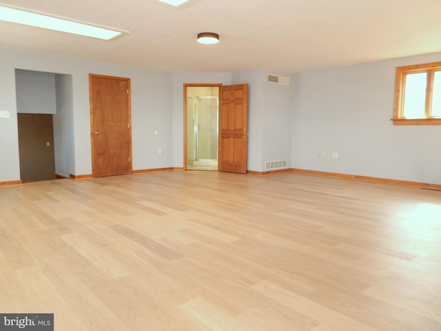 spare room with light wood-type flooring, visible vents, and baseboards