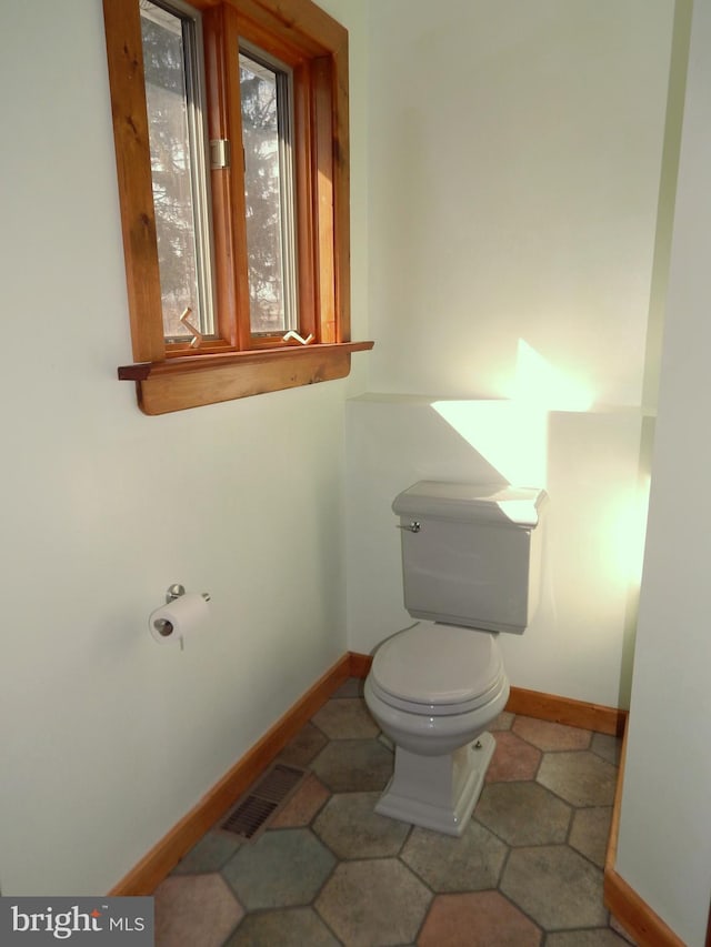 bathroom featuring toilet, visible vents, and baseboards