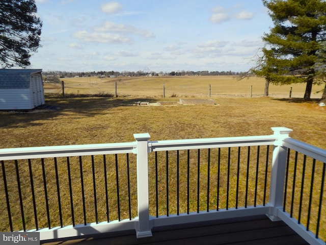 deck with an outbuilding, a storage shed, and a rural view