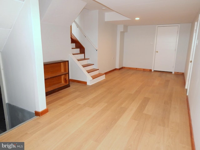 finished below grade area with stairs, light wood finished floors, recessed lighting, and baseboards