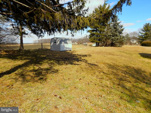 view of yard featuring a rural view, a storage unit, and an outdoor structure