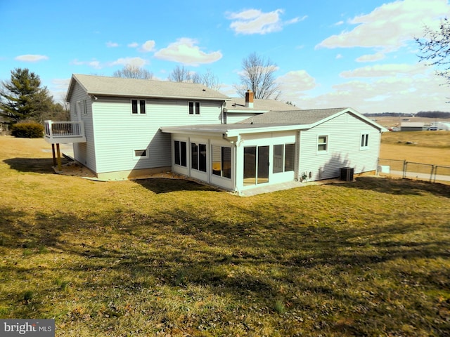 rear view of property featuring a yard, central AC unit, fence, and a sunroom