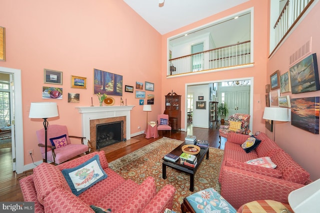 living room with a high end fireplace, visible vents, and wood finished floors