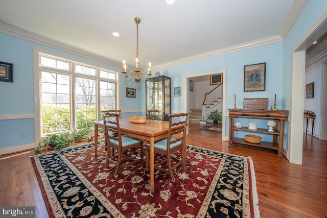 dining space featuring baseboards, ornamental molding, wood finished floors, stairs, and a chandelier