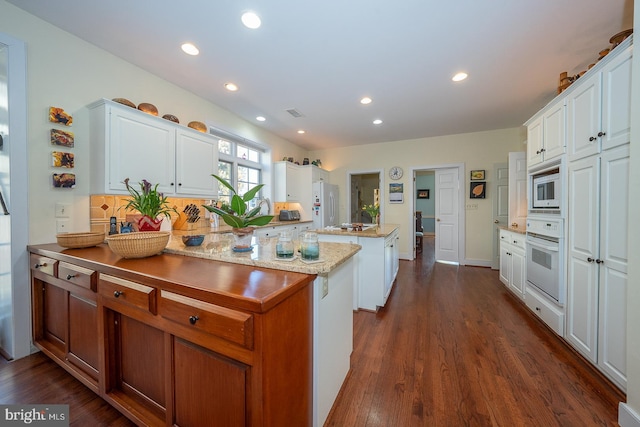 kitchen featuring white appliances, a kitchen island, white cabinetry, and dark wood-style flooring