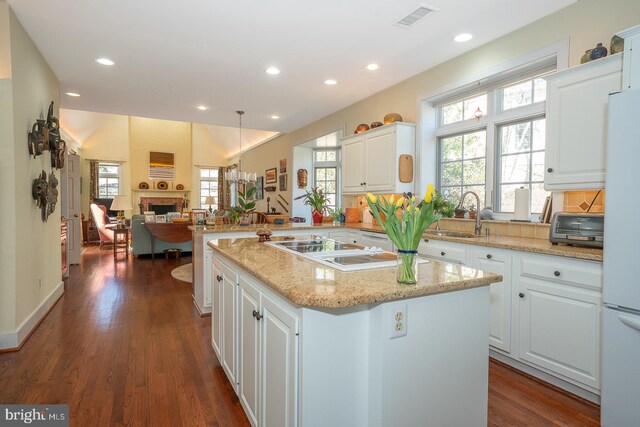 kitchen with a fireplace, visible vents, a sink, white appliances, and a peninsula