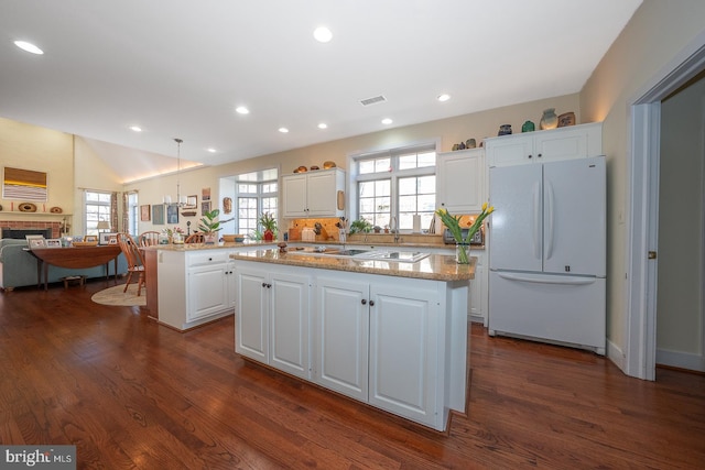 kitchen with white cabinetry, a fireplace, freestanding refrigerator, and a center island