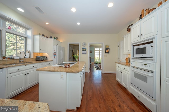 kitchen featuring white appliances, visible vents, dark wood finished floors, a kitchen island, and white cabinetry