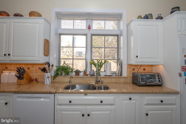 kitchen featuring white cabinets, dishwasher, backsplash, and a sink