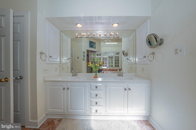 full bath featuring double vanity, baseboards, and a sink