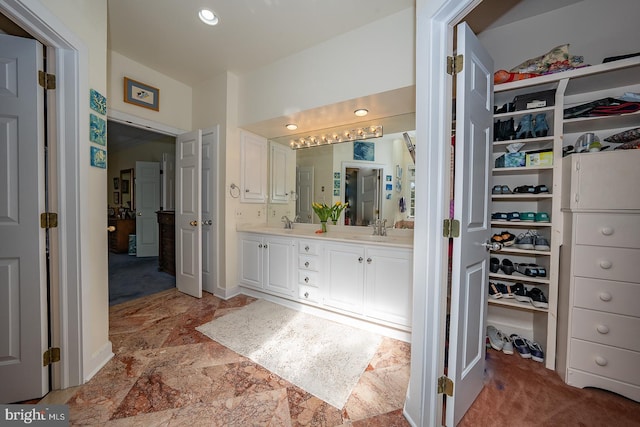 bathroom featuring a sink, a spacious closet, and double vanity