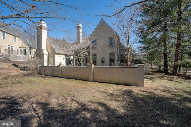 exterior space with a fenced front yard, a chimney, and stucco siding