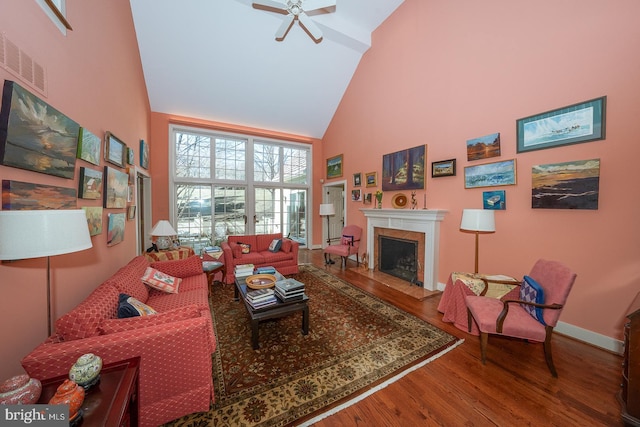 living room featuring baseboards, visible vents, wood finished floors, high vaulted ceiling, and a high end fireplace