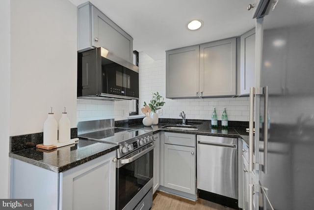 kitchen featuring backsplash, gray cabinets, stainless steel appliances, and a sink