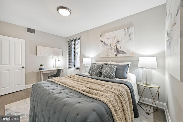 bedroom with visible vents, baseboards, and wood finished floors