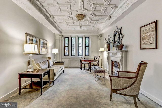 living area featuring an ornate ceiling, a fireplace, baseboards, and carpet flooring