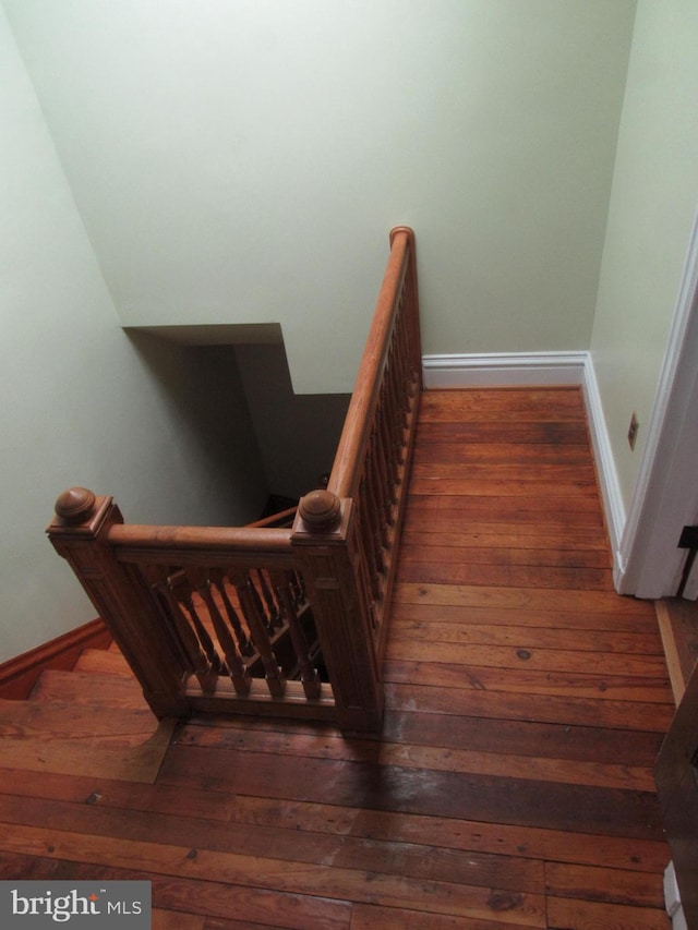 staircase with wood-type flooring and baseboards