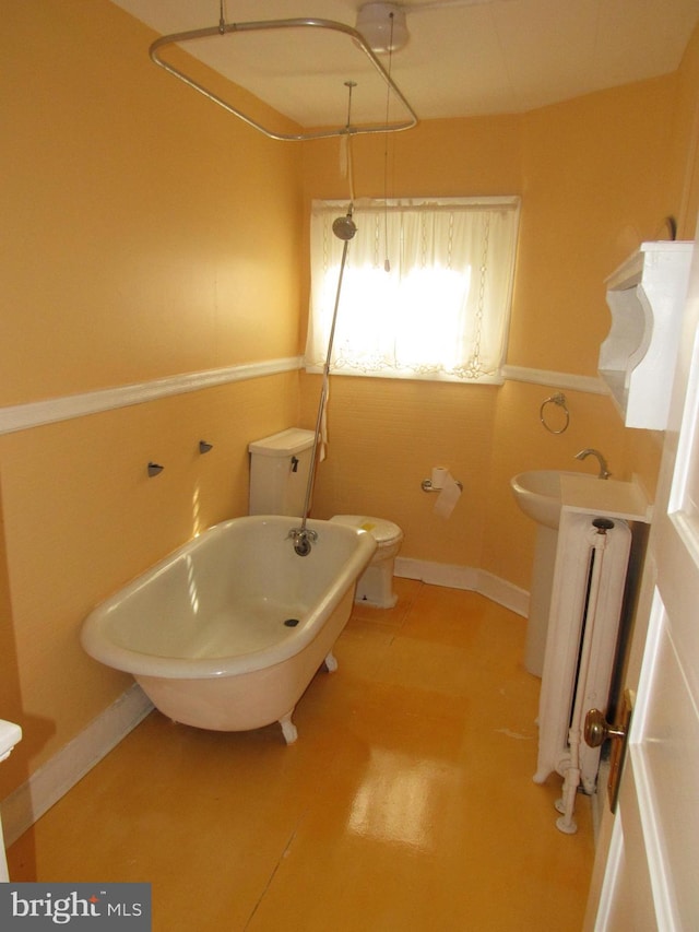 full bathroom featuring radiator, a soaking tub, toilet, a sink, and baseboards