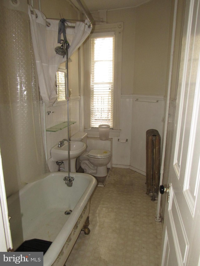 full bath with toilet, tile patterned floors, radiator heating unit, and wainscoting