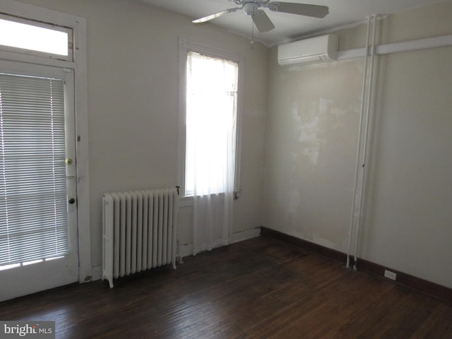 empty room featuring radiator, dark wood-type flooring, a ceiling fan, an AC wall unit, and baseboards