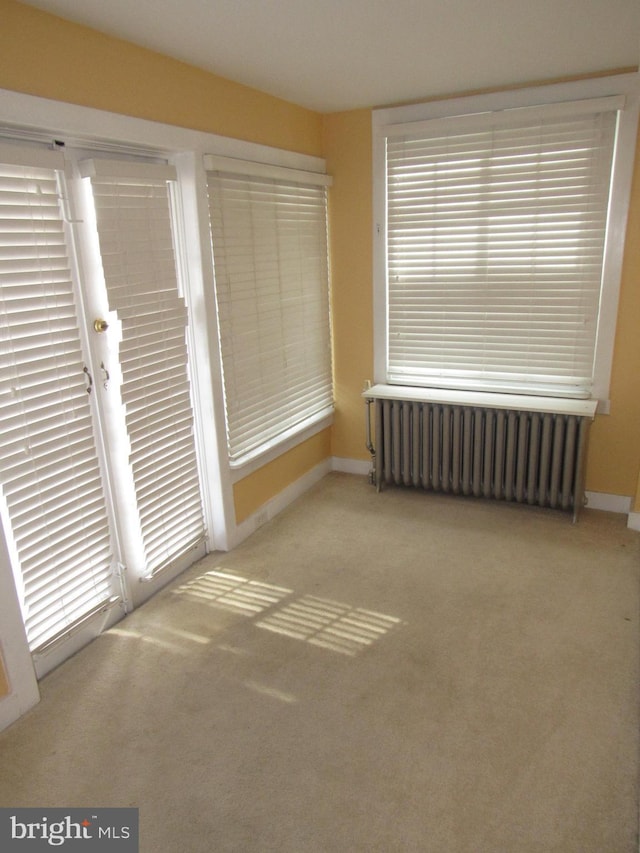 spare room featuring radiator, carpet, and baseboards