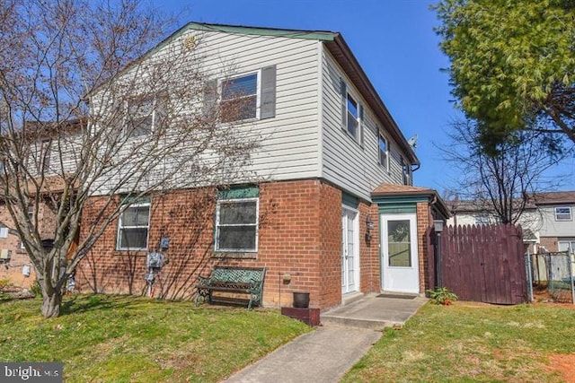 view of front facade with a front yard, brick siding, and fence