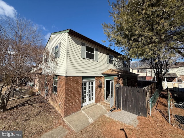 view of front of property featuring brick siding, fence, and french doors