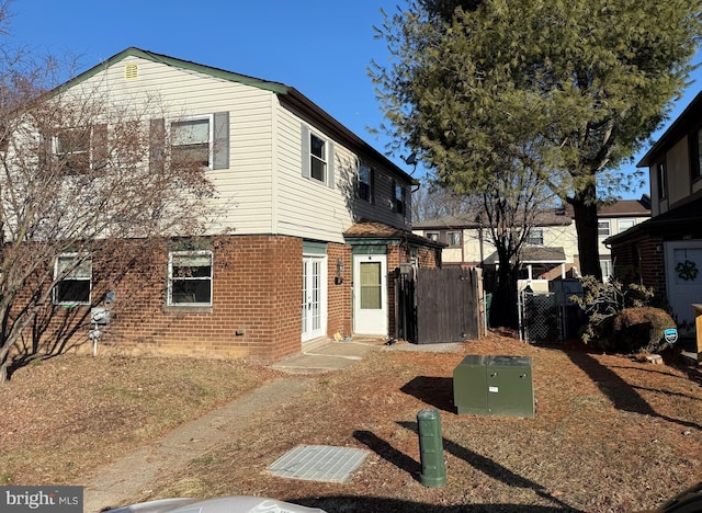 view of front of home with a gate, brick siding, fence, and french doors