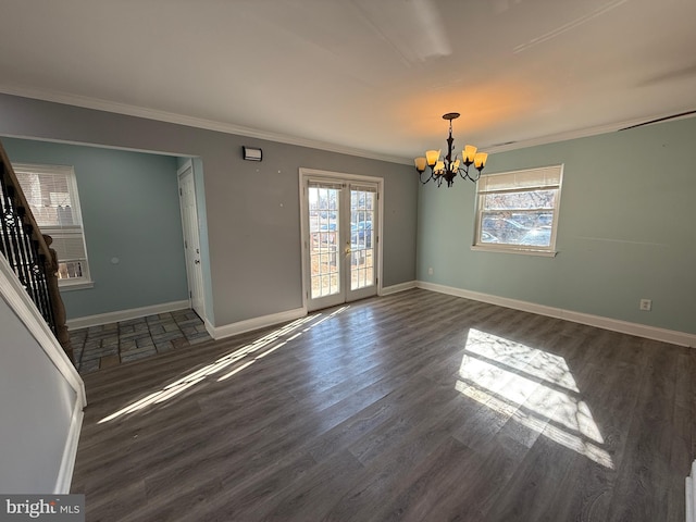 unfurnished room with a wealth of natural light, a notable chandelier, and wood finished floors