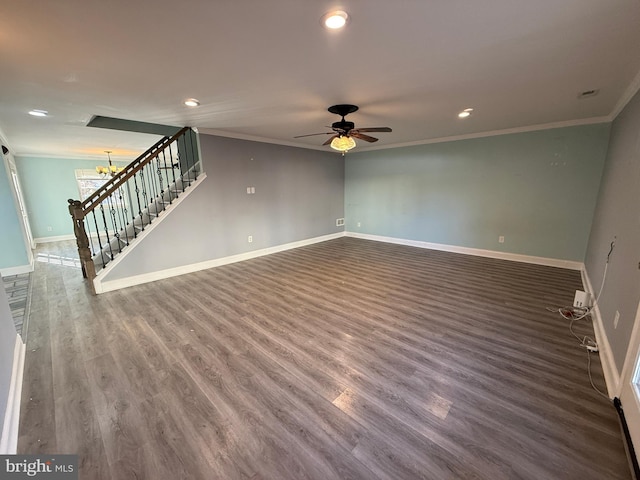 empty room featuring ceiling fan with notable chandelier, wood finished floors, baseboards, stairway, and crown molding