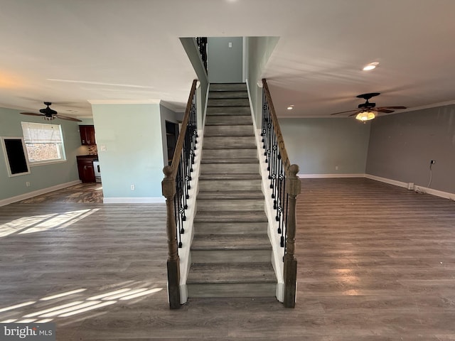 staircase with ornamental molding, ceiling fan, baseboards, and wood finished floors