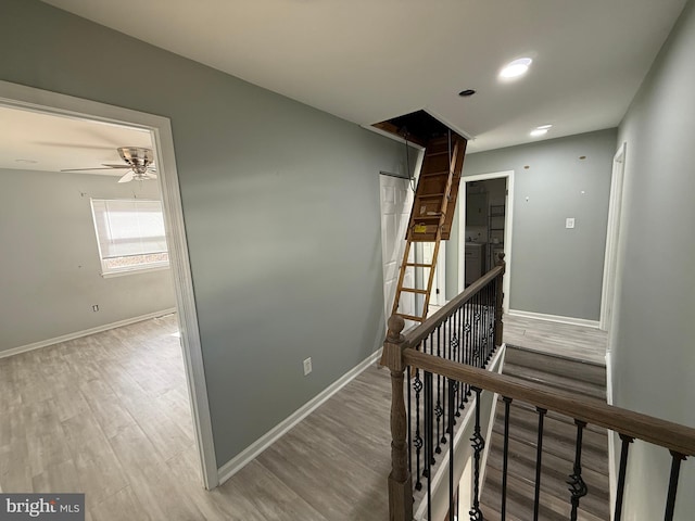 hallway with light wood finished floors, an upstairs landing, and baseboards