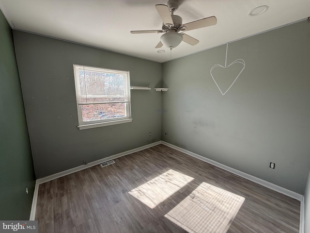 empty room with visible vents, ceiling fan, baseboards, and wood finished floors