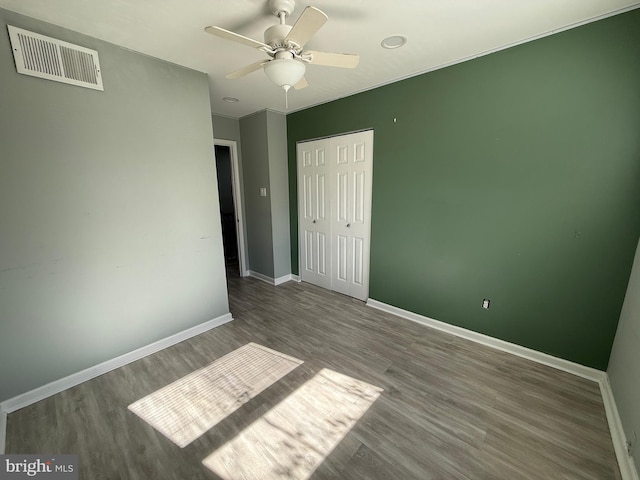 unfurnished bedroom with baseboards, visible vents, ceiling fan, wood finished floors, and a closet