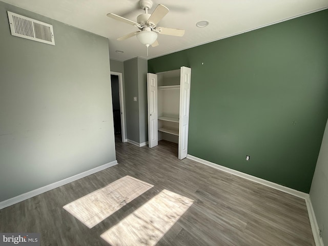 unfurnished bedroom featuring baseboards, visible vents, a ceiling fan, wood finished floors, and a closet