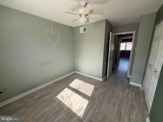 unfurnished bedroom with a closet, wood finished floors, visible vents, and baseboards