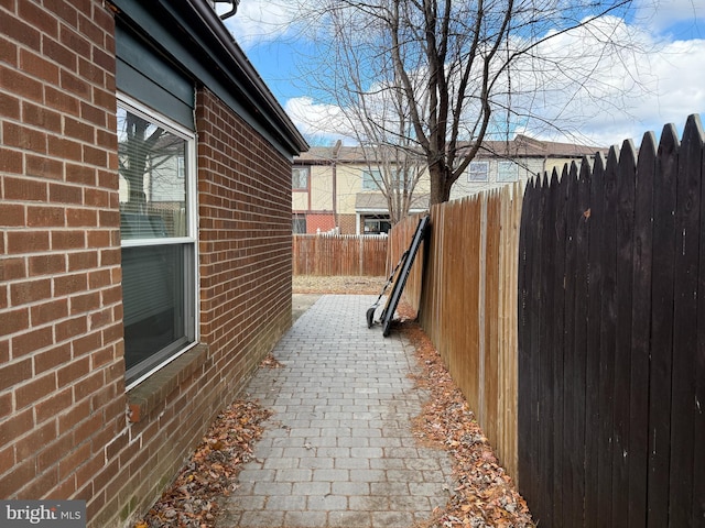 view of property exterior with brick siding and a fenced backyard