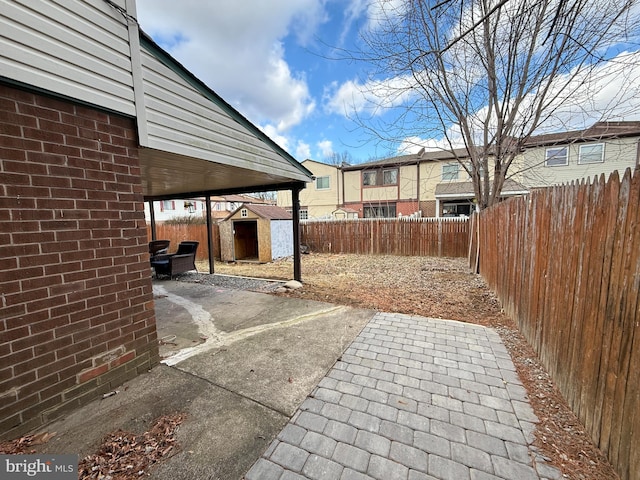 view of patio with an outbuilding, a fenced backyard, and a shed