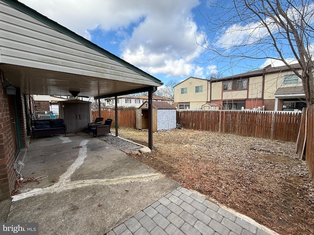 view of yard featuring a patio, a fenced backyard, a residential view, an outbuilding, and a storage unit