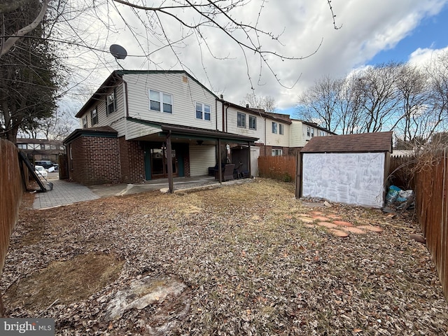 back of house with a fenced backyard, an outdoor structure, a patio, and a shed