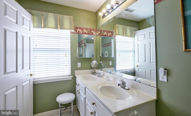 bathroom featuring double vanity, baseboards, visible vents, and a sink