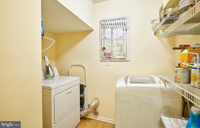 laundry room with laundry area, washing machine and clothes dryer, and baseboards