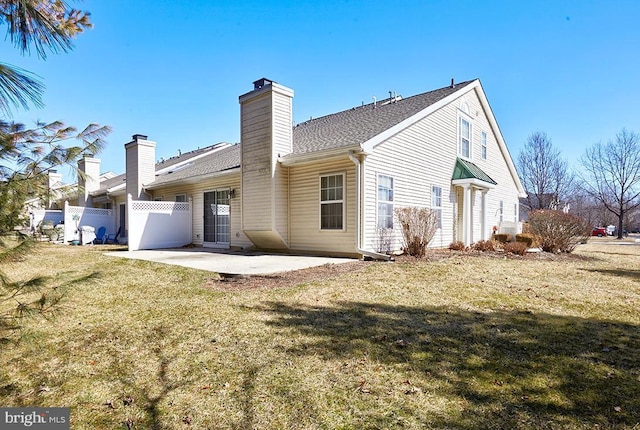 rear view of house with a patio area, a lawn, a chimney, and fence