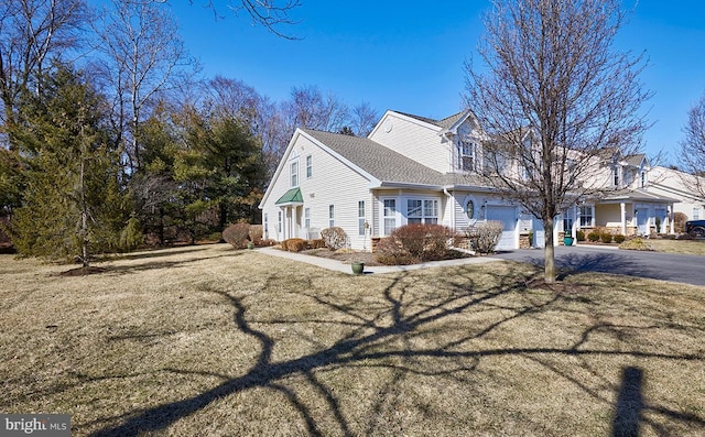 view of home's exterior featuring driveway, roof with shingles, a garage, and a yard